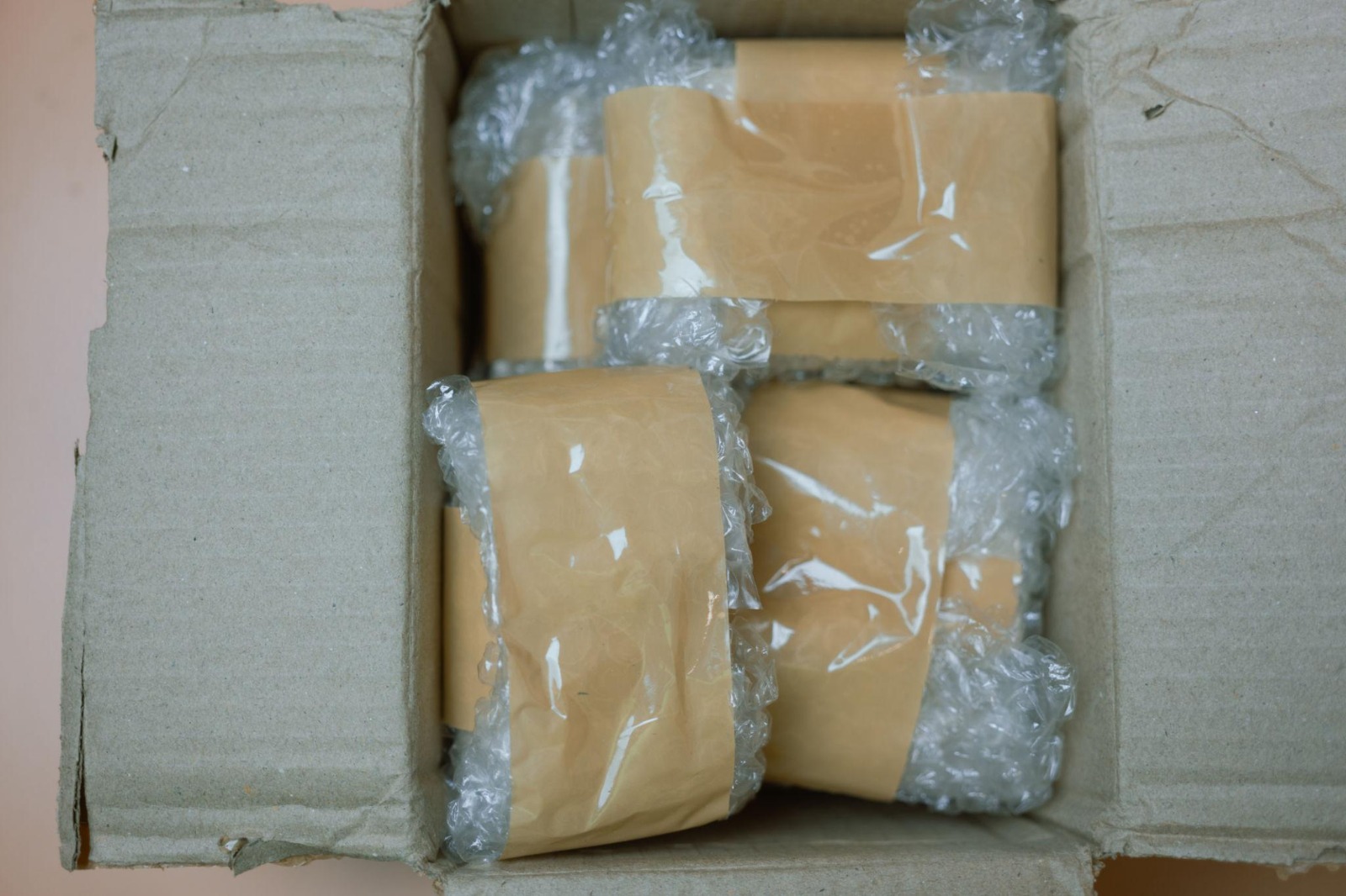Open carton with multiple items hand-wrapped in kraft paper and plastic film