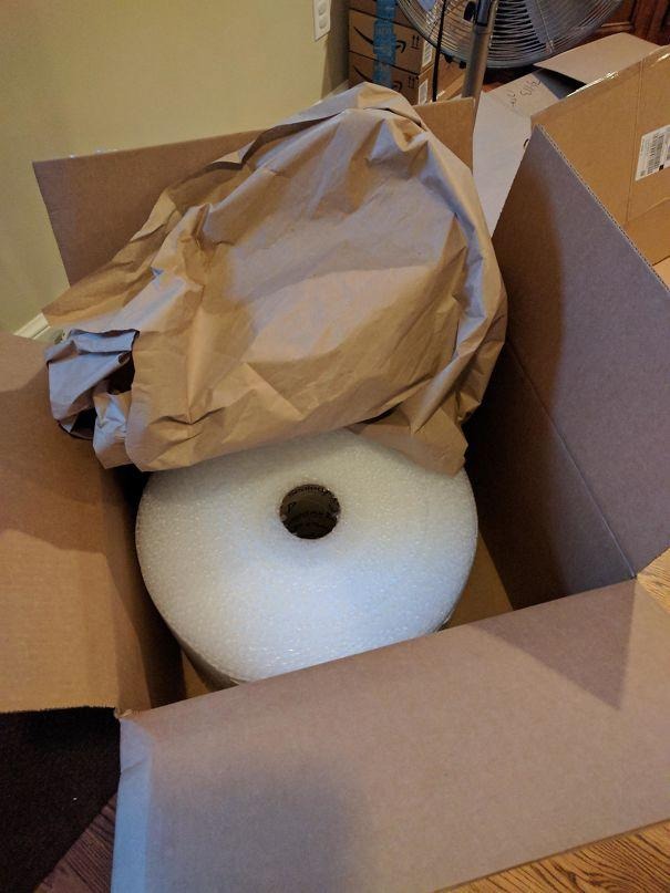 Open carton stuffed with crumpled kraft paper and a roll of bubble wrap