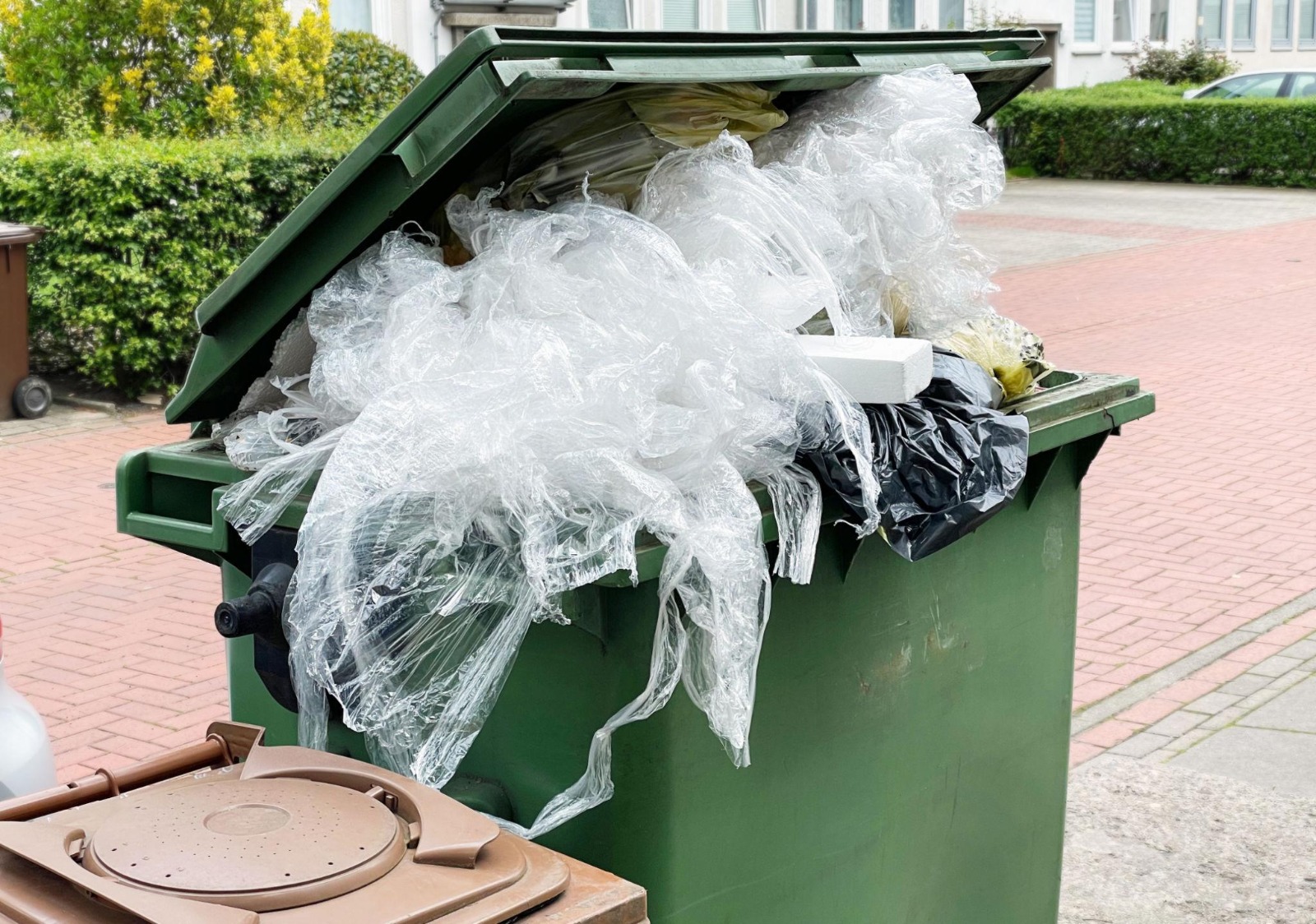 Outdoor dumpster overflowing with discarded plastic packaging film